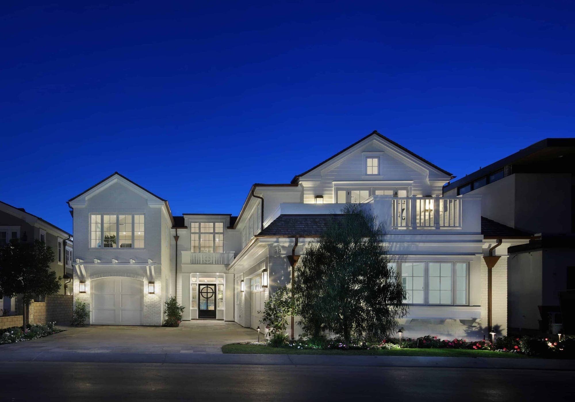A white two-story coastal home in Dana Point photographed at blue hour with lit interiors.