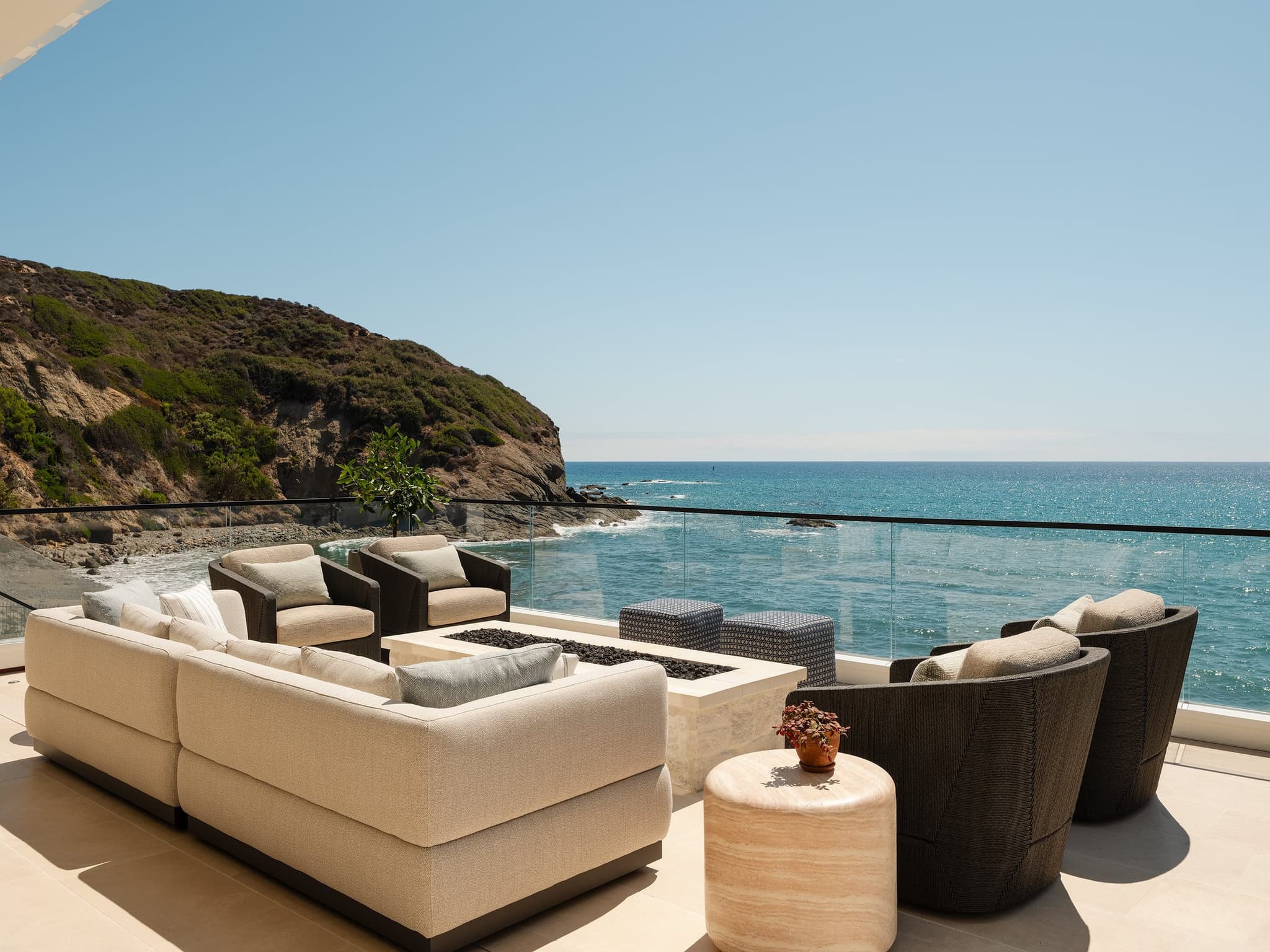 A sheltered terrace lounge opening to the ocean, sofas set toward the horizon.