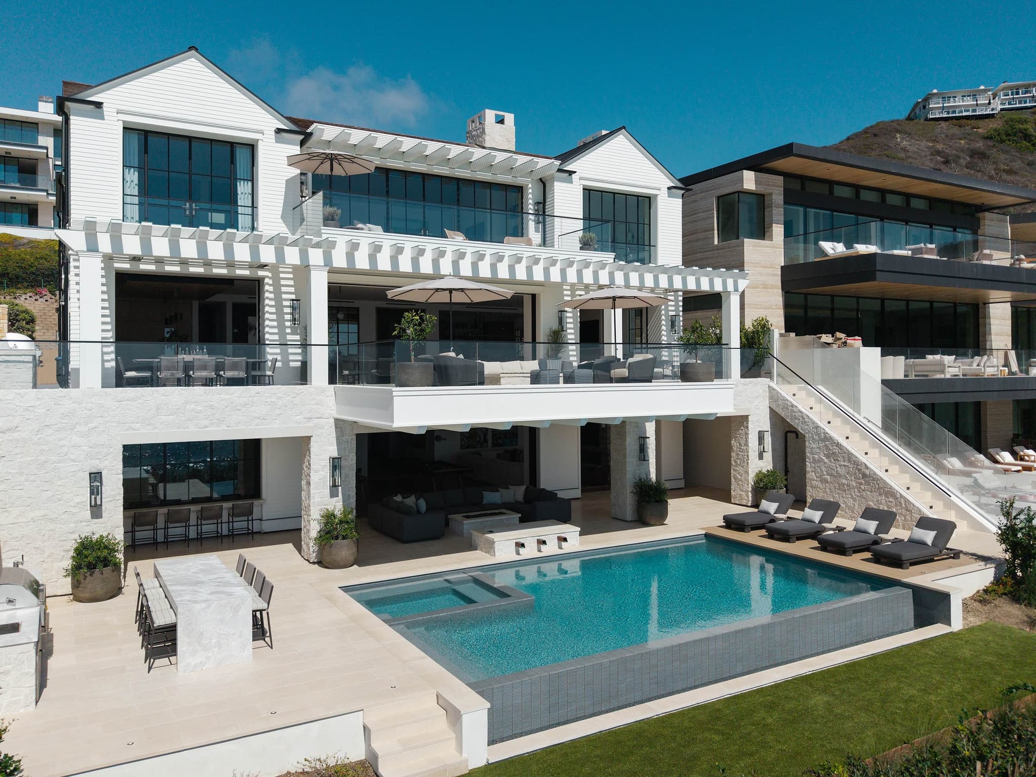 A living space opening to a pool terrace and the ocean through a wall of glass.